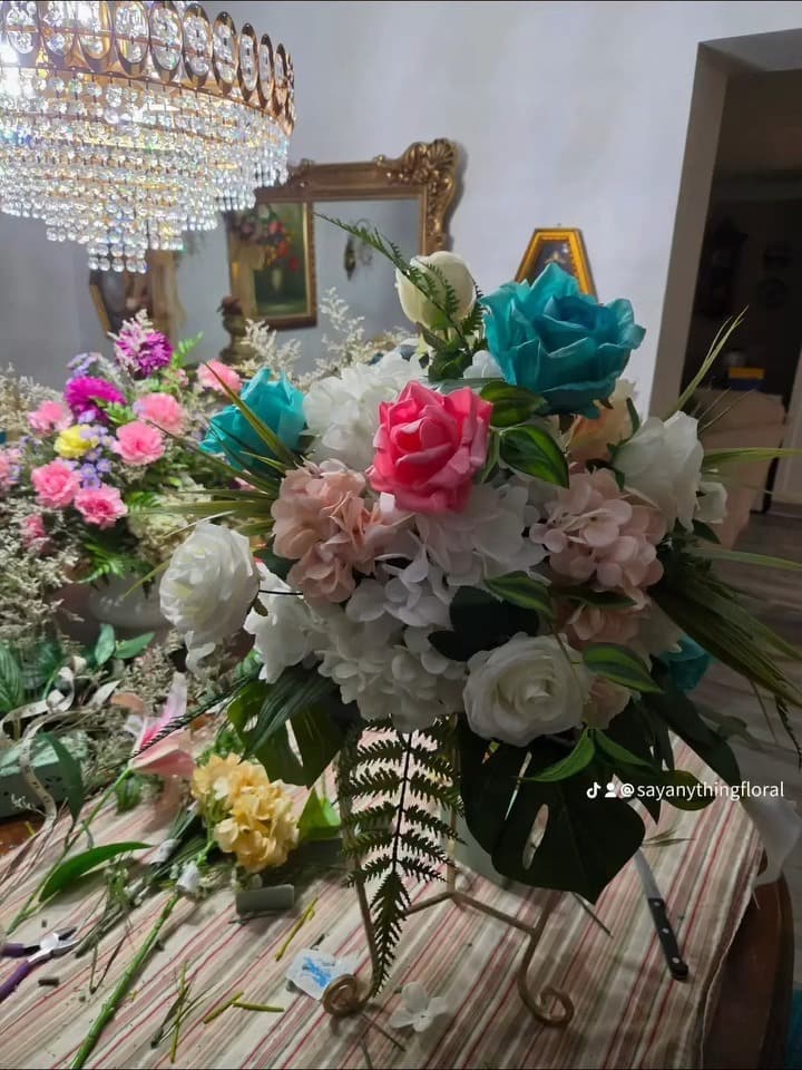 A centerpiece being built on the studio table, surrounded by loose stems and tools